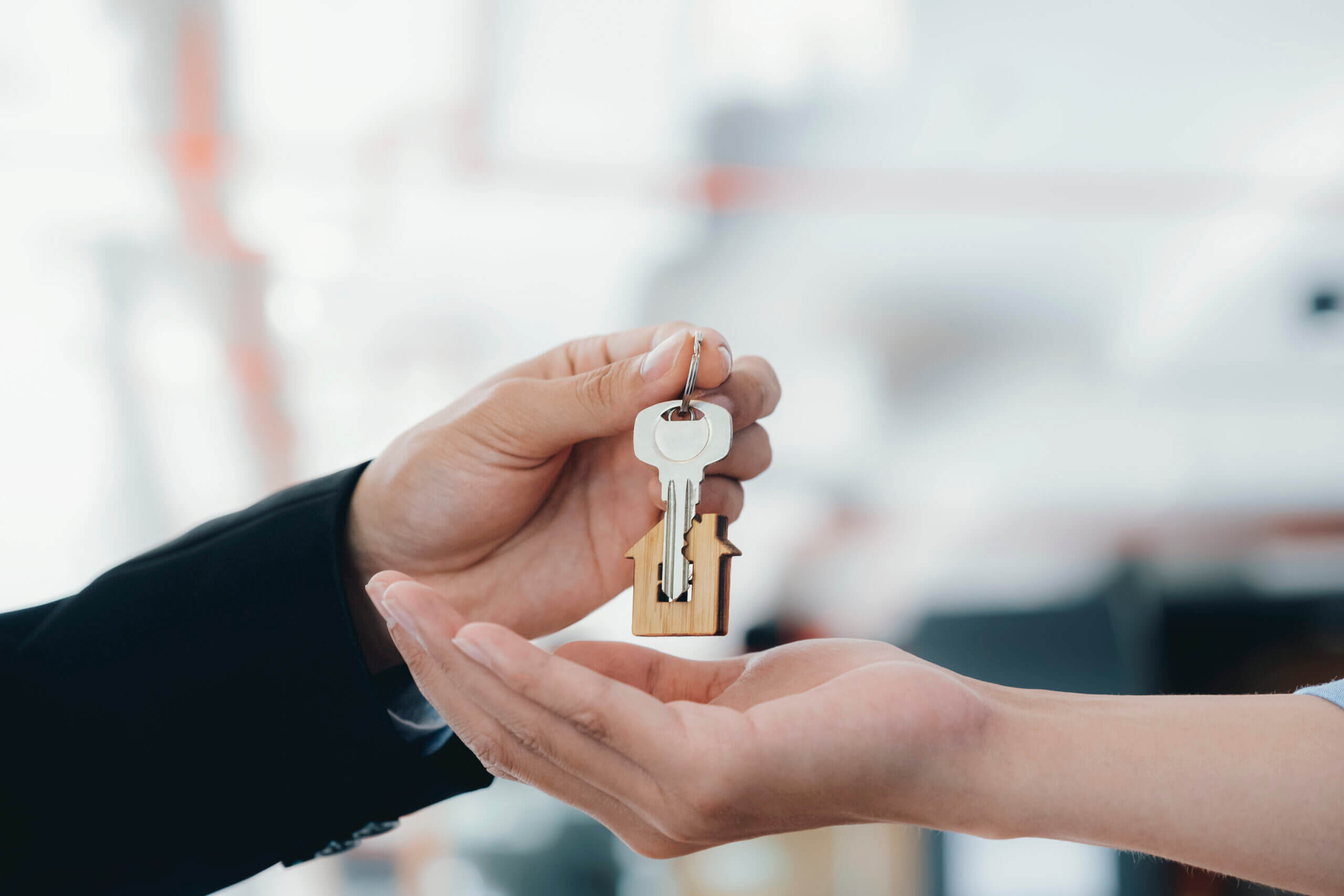 Real estate agent holding key with house shaped keychain.